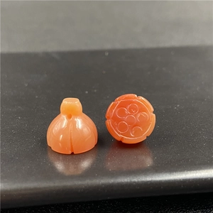 Dettaglio macro di perle in agata arancione intagliate a forma di melograno e loto
