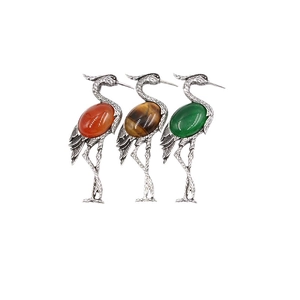 Three vintage crane brooches with inlaid red, green, and brown gemstone cabochons