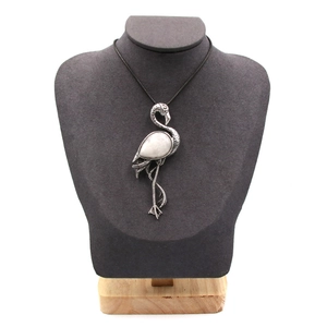 Collana con ciondolo fenicottero e pietra bianca su espositore per gioielli grigio