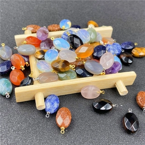 Macro view of assorted oval faceted gemstone pendants with metal rings on wood tray