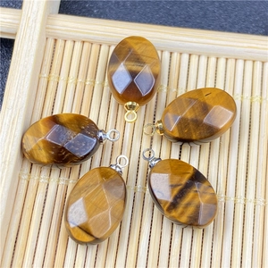 Detailed view of faceted oval tiger eye stone pendants with metal loops on bamboo mat