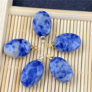 Faceted oval blue sodalite pendants with gold and silver metal bails on bamboo mat