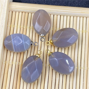 Detailed view of oval agate pendants with geometric carvings on a bamboo mat background