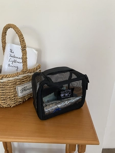 Close-up of black mesh cosmetic bag on wooden table showing spacious storage capacity