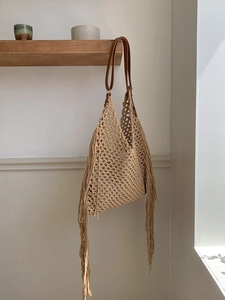 Macro shot of boho woven tote bag featuring long tassels and premium leather straps