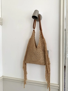 Detail of bohemian hollow woven tote bag featuring fringe tassels and leather strap