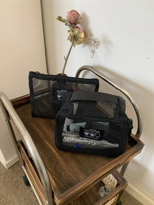 Detail view of black mesh toiletry bags on a wooden cart with dry floral accents