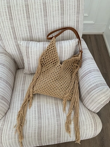 Detail of bohemian hollow knit tote bag featuring long side tassels and leather strap