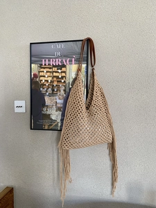 Close-up of bohemian hollow woven tote bag featuring beige crochet and long tassels