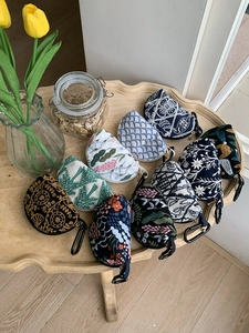 Detailed embroidery on small canvas pouches with floral patterns and metal hooks