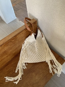 Detail of woven mesh texture and long bohemian tassels on a cream tote bag