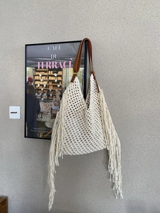Detail of bohemian knit tote bag featuring large mesh patterns and long tassel fringe