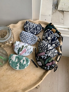 Set of 7 embroidered half-moon coin purses with metal clips on a vintage wooden tray