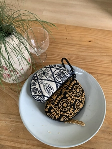 Detail of floral embroidery on small pouches with metal carabiners on a blue tray