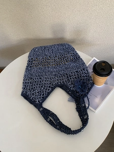 Details van een donkerblauwe holle geweven handtas met bloemhanger en kralenversiering