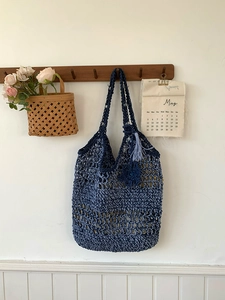 Detail van blauwe gehaakte schoudertas met bloemenhanger en franje decoratie