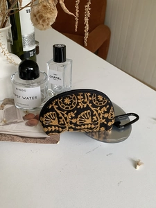 Detail of vintage floral embroidery on black canvas pouch with metal carabiner