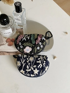 Close-up of semi-circular embroidered pouches with floral patterns and zipper closure