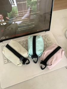 Trois mini pochettes en nylon colorées avec clips en D posées sur un ordinateur portable