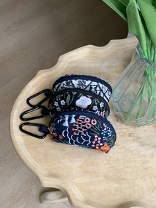Detailed embroidery on three mini pouches with floral patterns and carabiner hooks