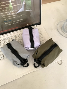 Trois pochettes en nylon gris, lavande et vert avec mousquetons métalliques