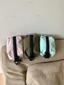 Détail des pochettes en nylon rose, vert et olive avec mousquetons de fixation