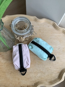 Pochettes en nylon rose et vert avec mousquetons noirs sur table en bois détail