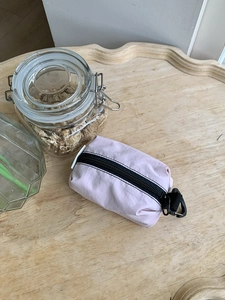 Mini pochette rose en nylon avec fermeture noire et mousqueton sur table en bois