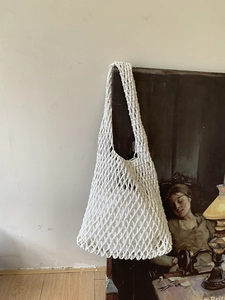 Detail of white hand-woven mesh tote bag with inner lining against artistic frame