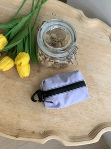 Vue de dessus d'une pochette en nylon lilas clair avec crochet noir sur plateau en bois