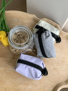 Trois mini pochettes en nylon coloré avec crochets disposées sur un plateau en bois
