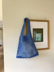 Detail showing blue hand-woven mesh tote bag with intricate rope knotting design