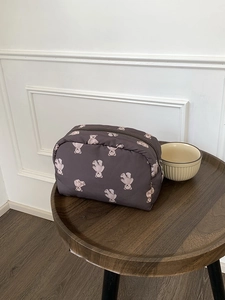 Cute dark brown bear print makeup bag with large capacity and zip closure on wooden table