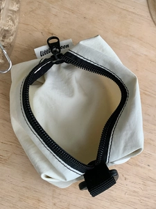 Pochette minimaliste en nylon beige pour écouteurs et clés sur table en bois