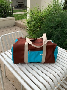 Detail of color-block nylon tote bag with reinforced handles and durable zipper