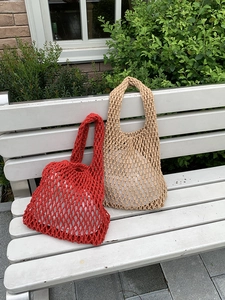 Detail of red and beige hand-woven mesh tote bags on a rustic outdoor bench