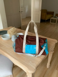 Detail view of the two-tone nylon tote bag featuring durable handles and front zipper pocket