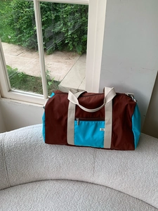 Close-up of color-block nylon tote bag with blue pocket on white fleece sofa