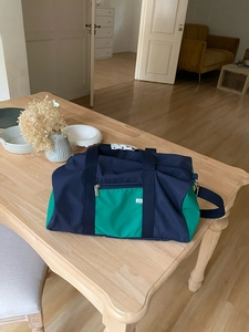 Detail of navy and green nylon tote bag featuring front zipper pocket and webbed handles