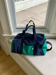 Detail of multi-color nylon sports bag featuring deep blue and green panels with front zipper