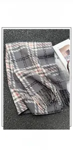 Dettaglio della morbida trama in finta cashmere e delle frange della sciarpa a quadri
