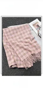 Detail of pink and yellow plaid scarf with soft fringe on an asphalt background