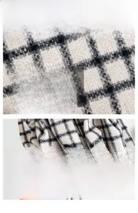 Detail of black and white plaid scarf featuring soft knit texture and fringe edges