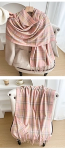 Detail of pink and yellow plaid scarf with soft fringe on a beige wool coat