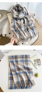 Detail showing soft cashmere-like texture and blue-brown checkered pattern scarf with tassels