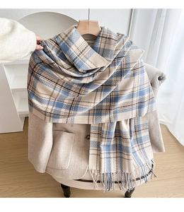 Close-up of blue and brown plaid scarf texture with soft fringe on beige coat
