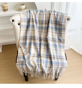 Detailed view of plaid scarf with tassels draped on a white chair in a home setting