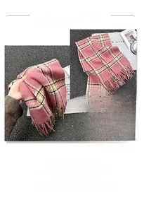 Close-up of pink plaid scarf texture with soft fringe details and thick tassels
