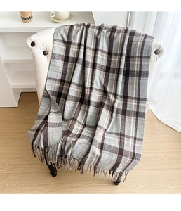 Close-up of thick plaid scarf with tassels in brown, grey, and beige on a white chair