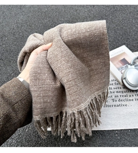 Detailaufnahme eines braun gewebten Winterschals mit langen Fransen und Textur